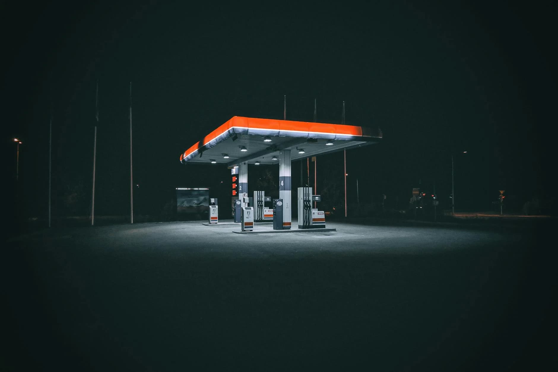 An isolated and illuminated gas station at night, highlighting urban solitude under a dark sky.