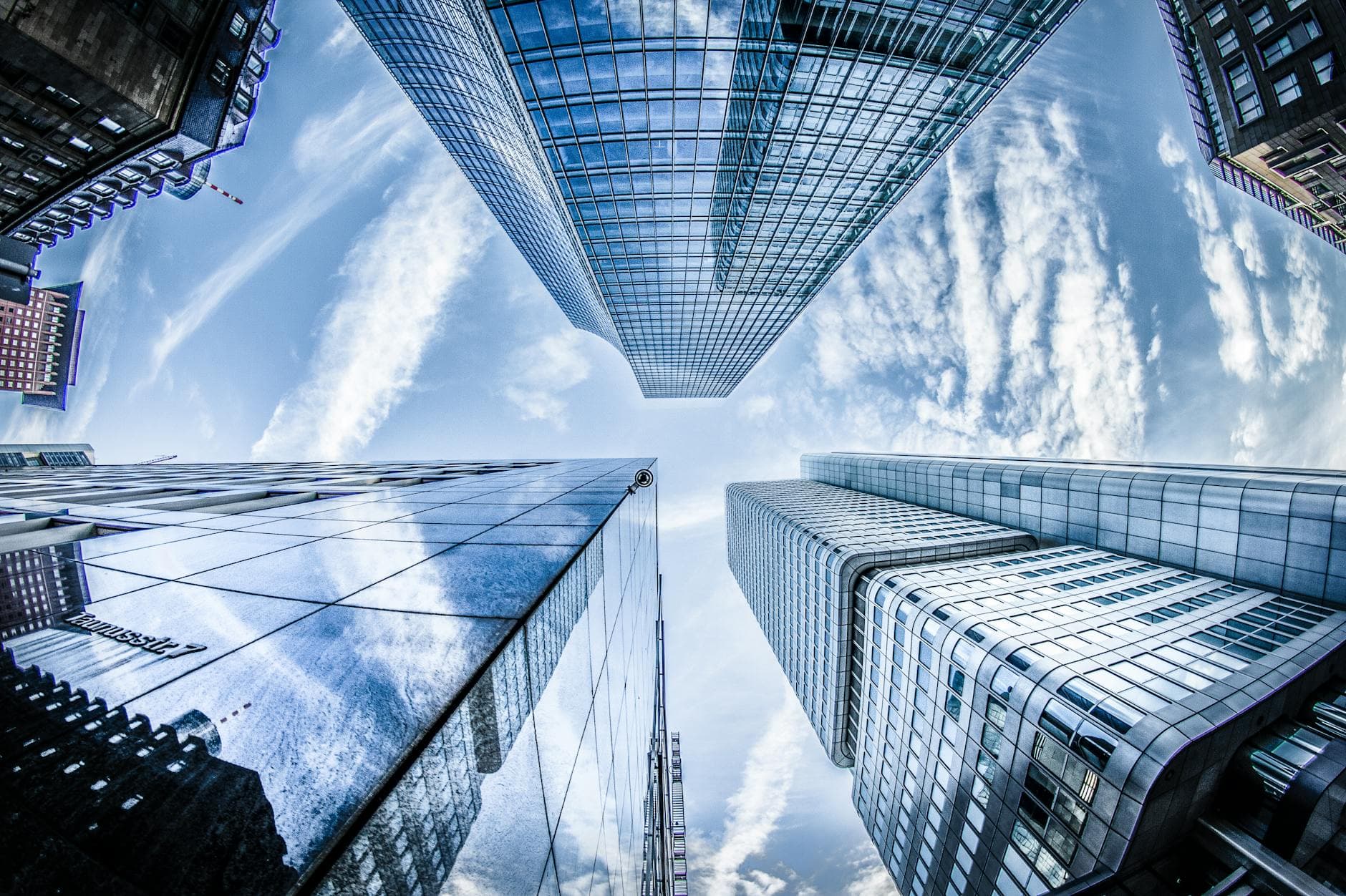 Low angle shot of modern skyscrapers in Frankfurt, showing reflections and sky.