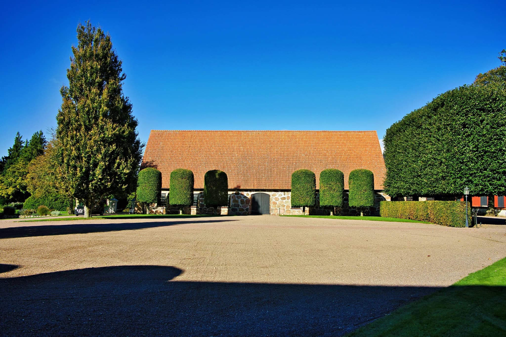 Barn with manicured trees under a clear blue sky