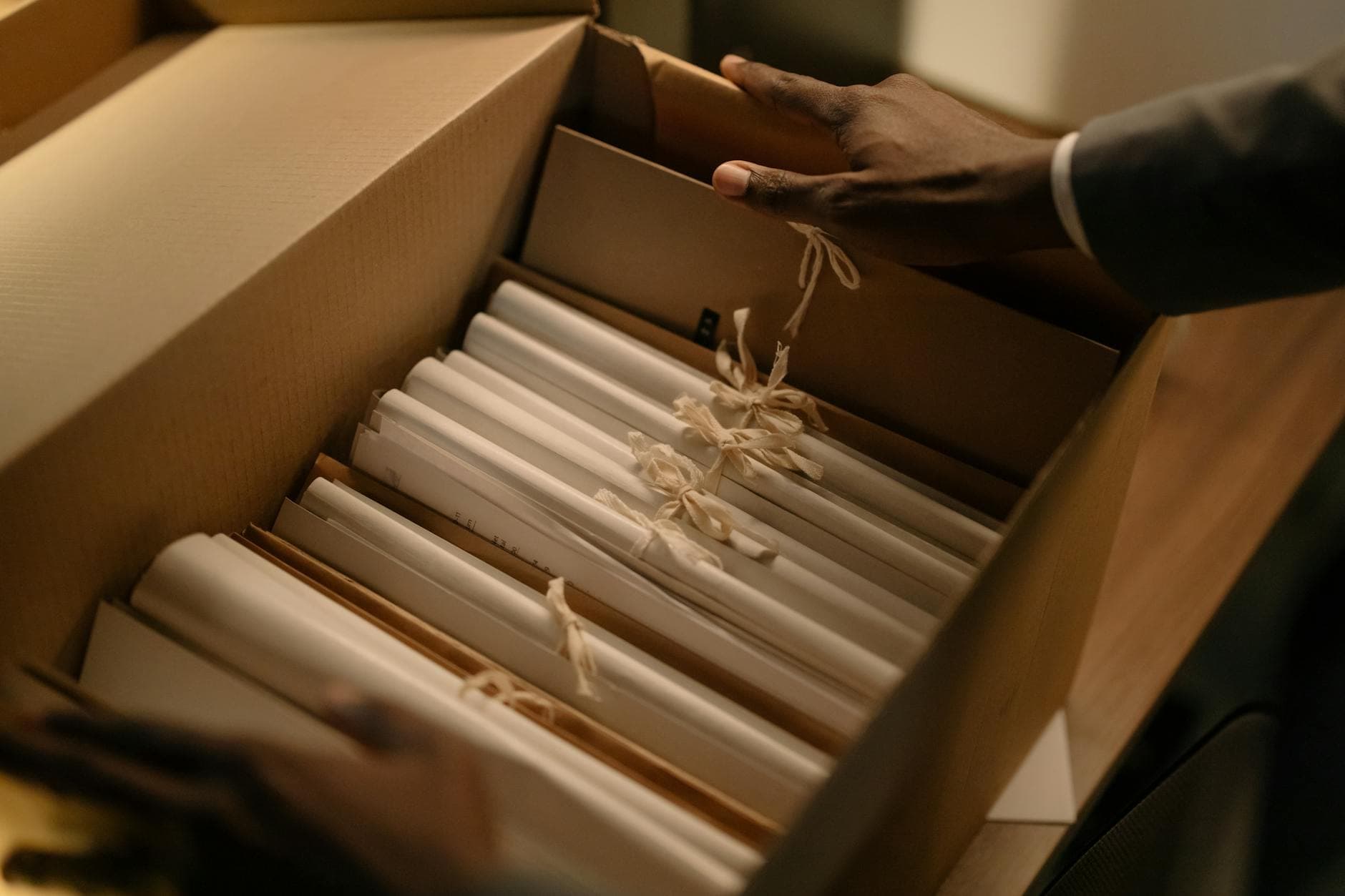 Hands organizing files in a box, symbolizing investigation and research.