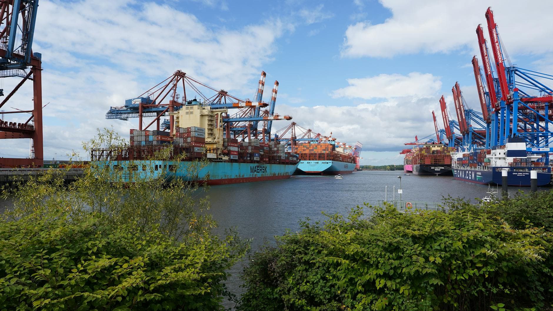 Large container ships docked at Hamburg port under a clear blue sky, showcasing global trade.