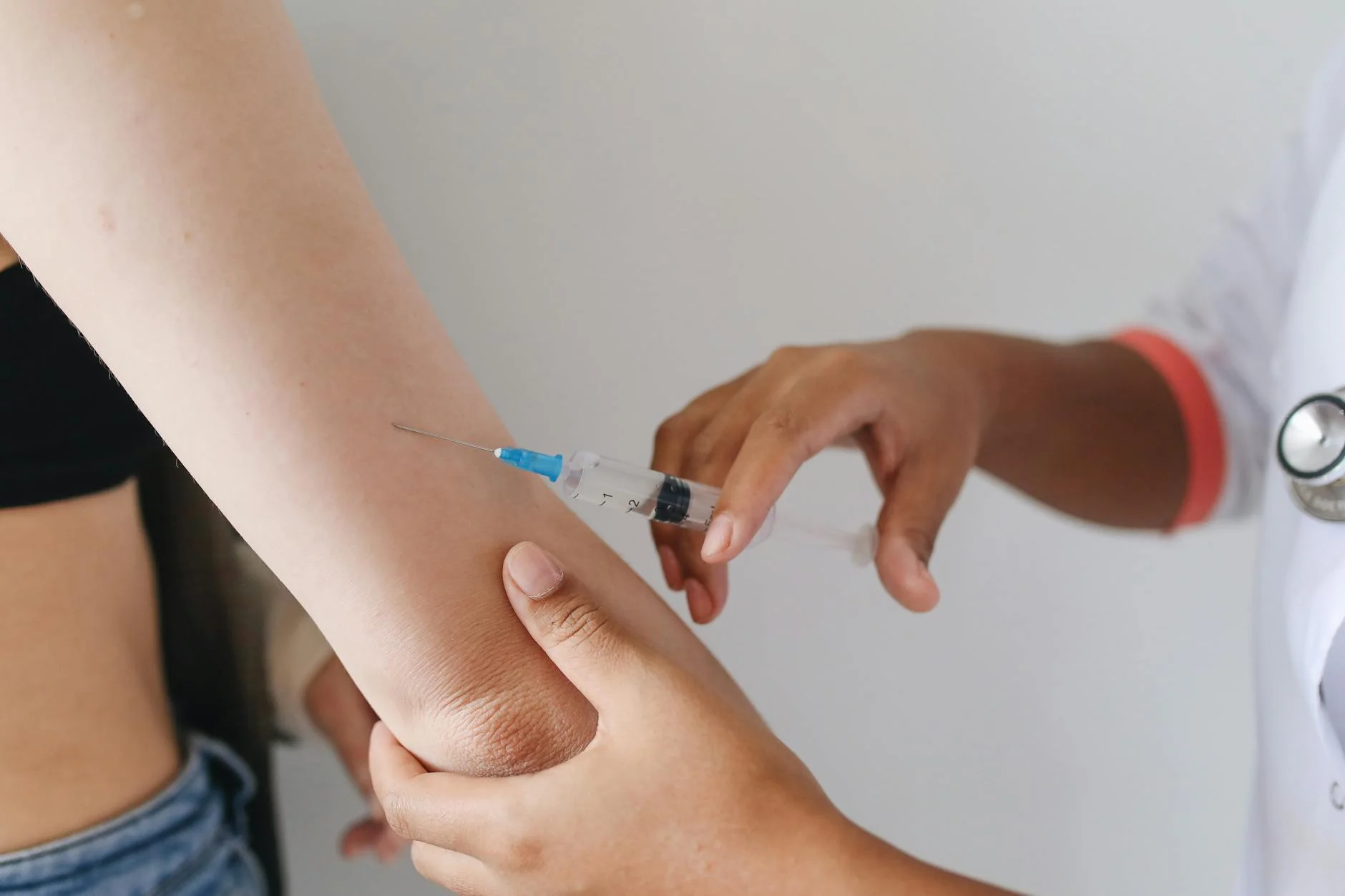 Doctor administering an injection to a patient's arm, close-up view.