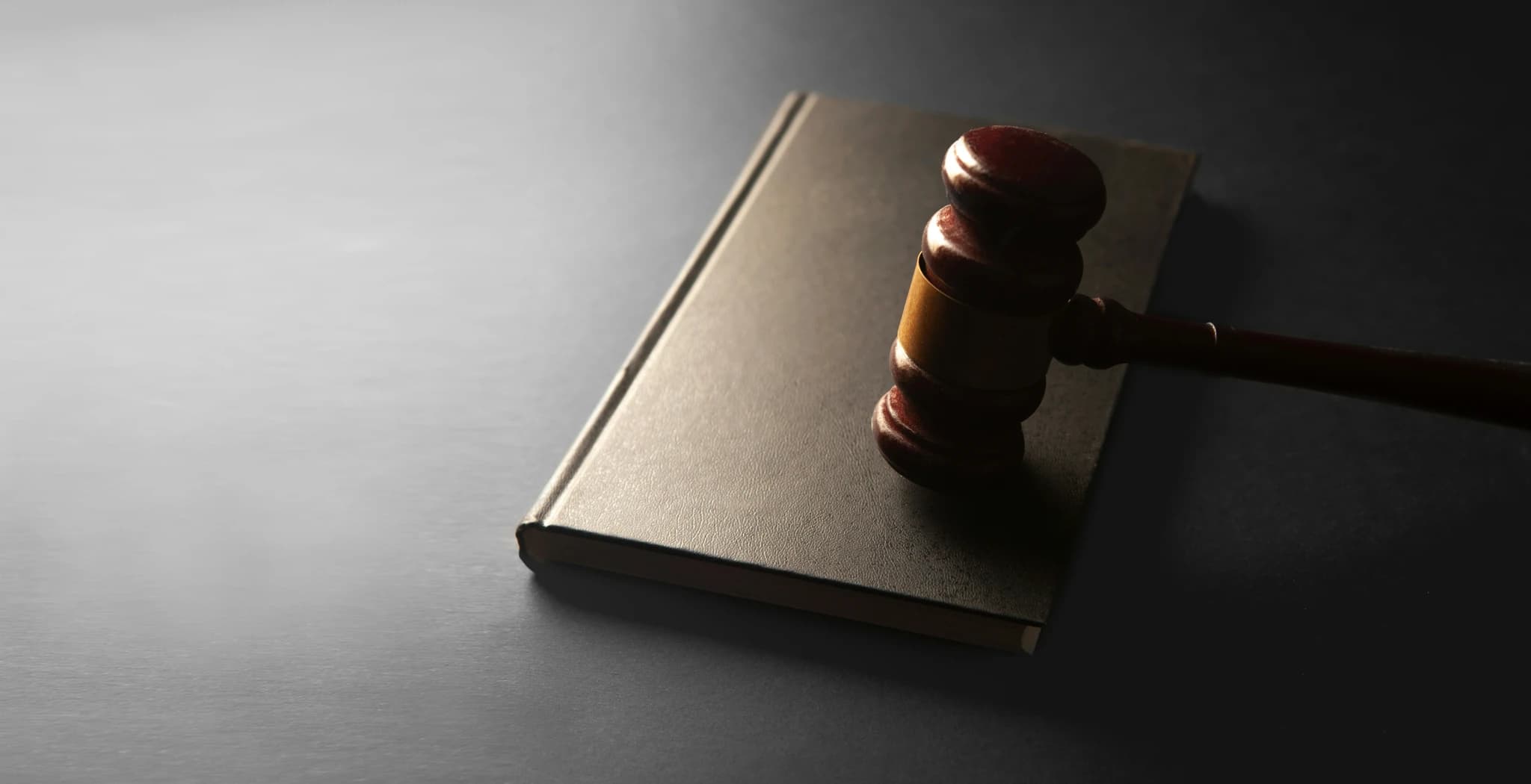 A wooden gavel rests on a closed book.