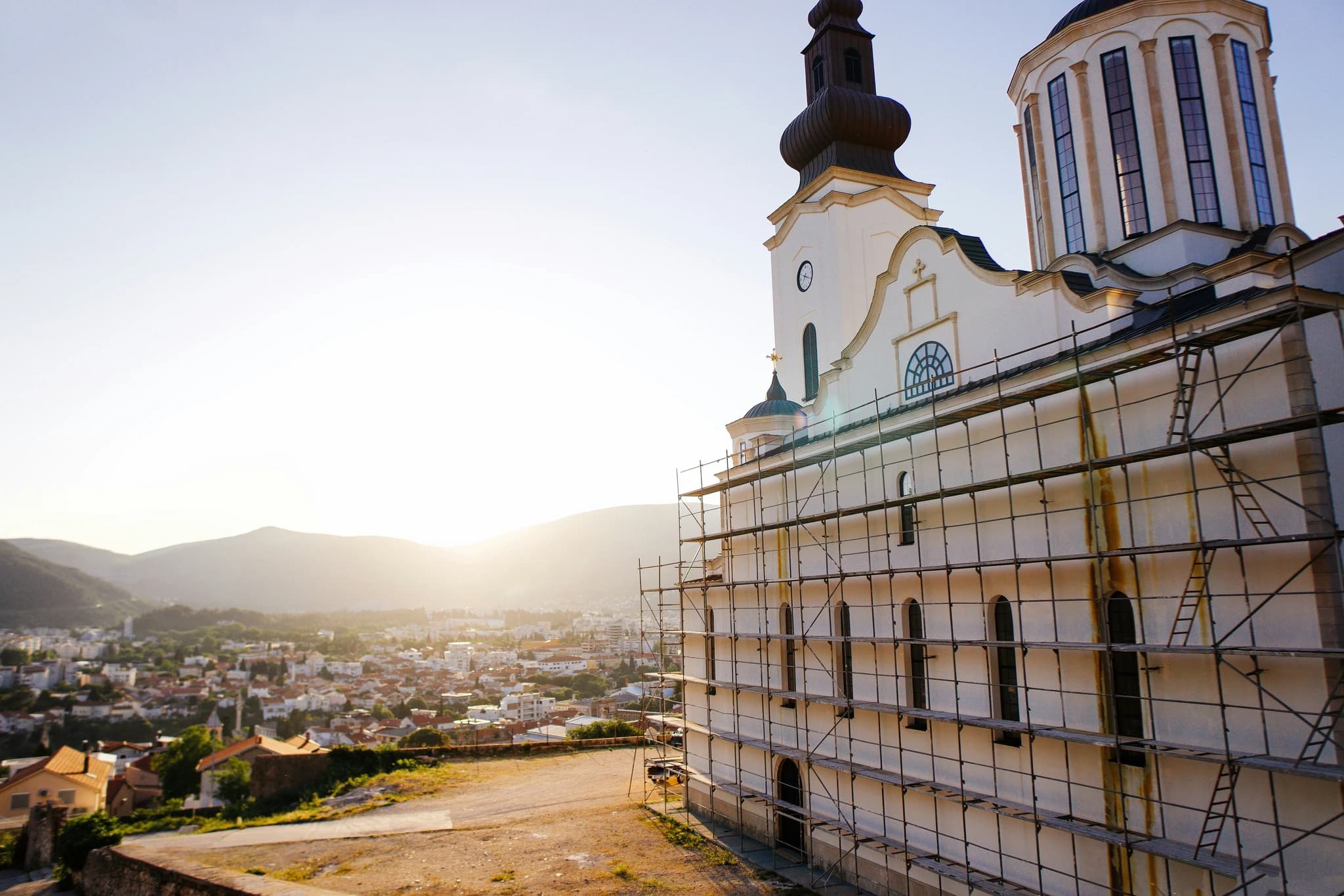 a church with scaffolding around it and a city in the background