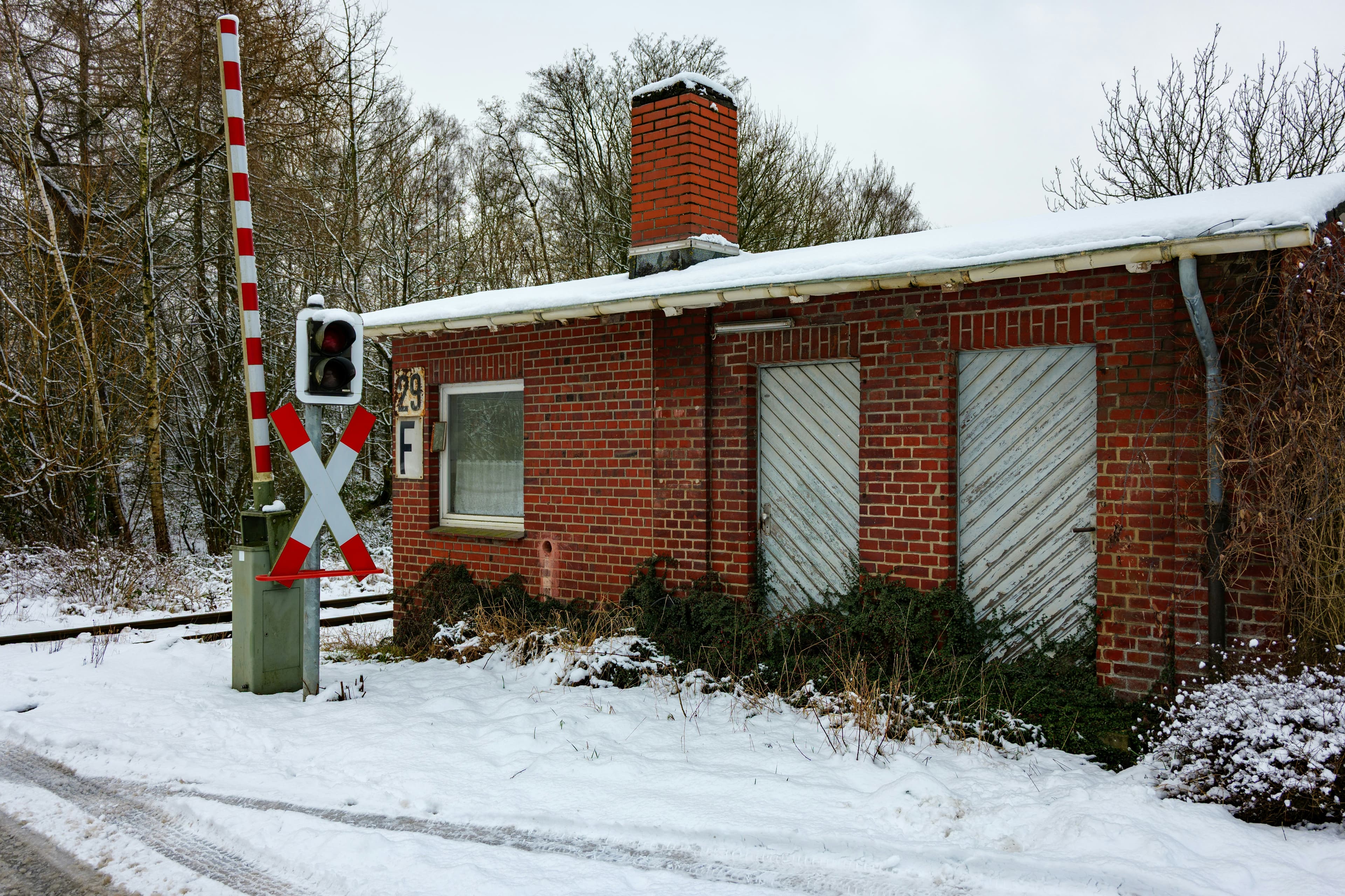 Brick building with railroad crossing gate in snow