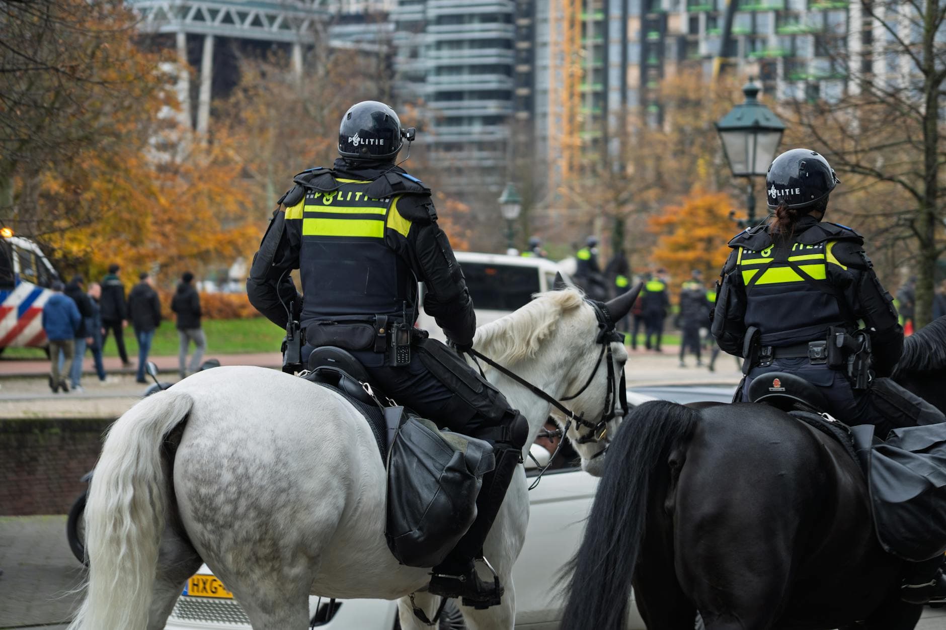 Police officers on horseback patrol an urban area in autumn, maintaining public peace.
